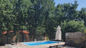Un patio trasero con piscina, sillas de descanso y valla de madera.