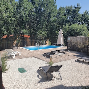Un jardin avec une piscine, des chaises longues et une clôture en bois.