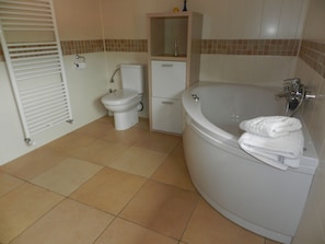 Une salle de bain équipée de toilettes, d’un lavabo et d’une baignoire, avec des serviettes à disposition.
