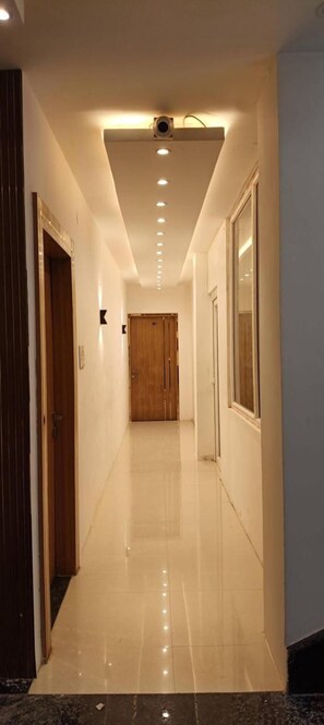 Un pasillo con piso pulido, iluminación empotrada y una puerta de madera al final.