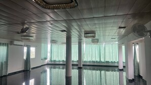 A spacious hall with a polished floor, large windows with curtains, and ceiling fans. - Hotel Krishna & Restaurant (Barharwa)