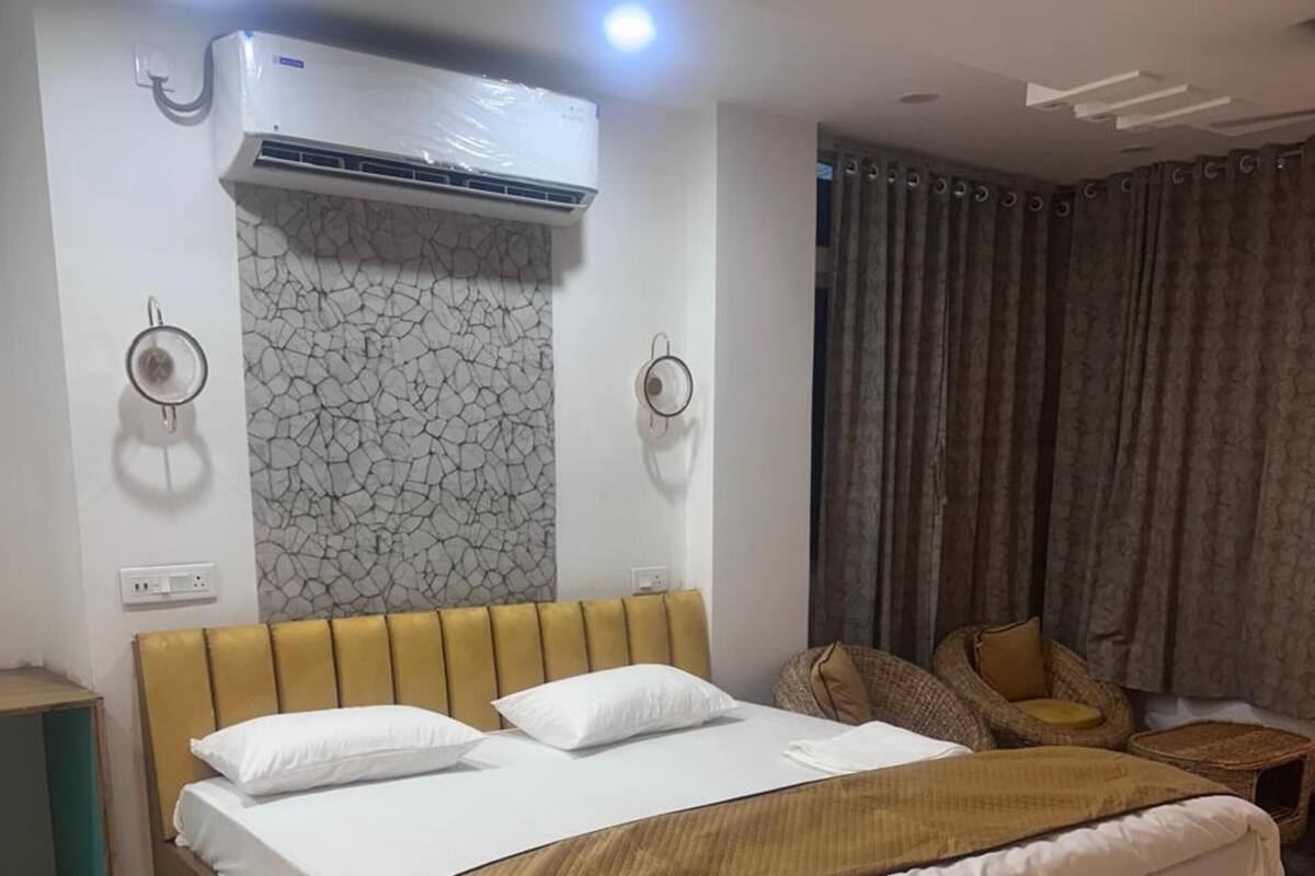 A bedroom with a bed, bedside tables, an air conditioning unit, and a patterned wall.