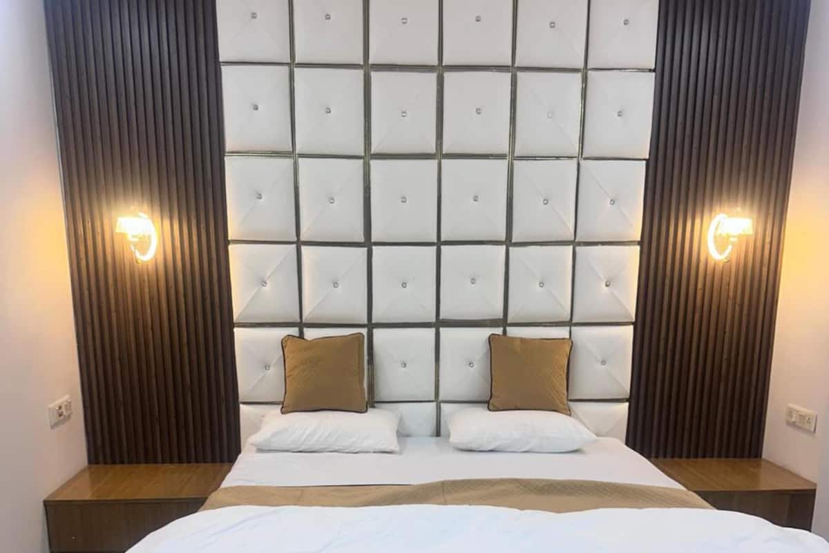 A bedroom with a large bed, wooden headboard, and two bedside tables.