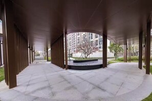A covered outdoor area with a curved pathway, a central circular planter with a tree, and tall residential buildings in the background. - Ge Rui  ApartmentFutian Shenzhen. (Futian District, Shenzhen.)