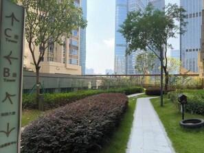 A pathway flanked by greenery and modern buildings, with directional signs indicating tower locations. - Ge Rui  ApartmentFutian Shenzhen. (Futian District, Shenzhen.)