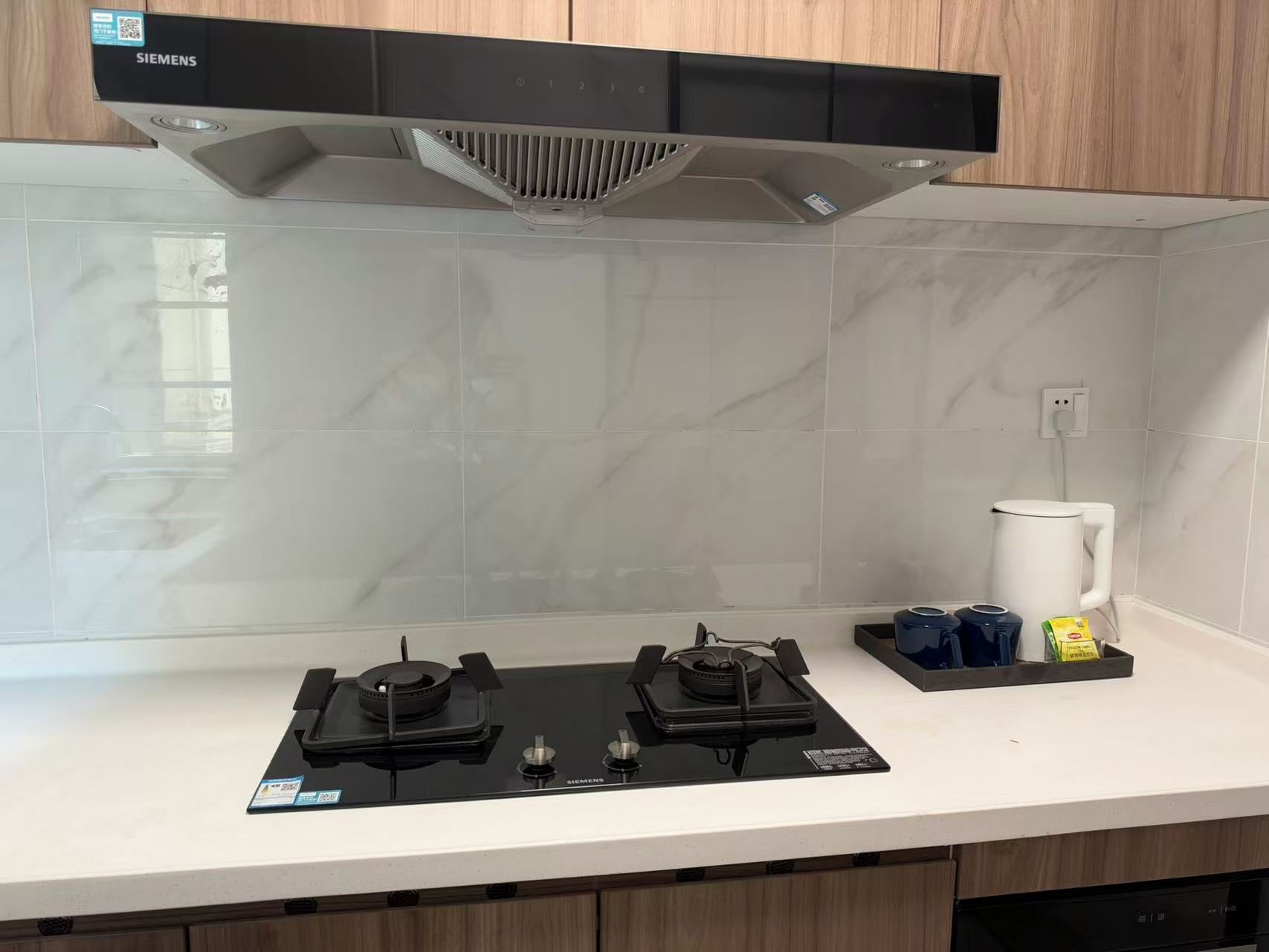 Cozinha com design moderno, destacando um exaustor Siemens preto, fogão elétrico duplex e painel de azulejos brancos.