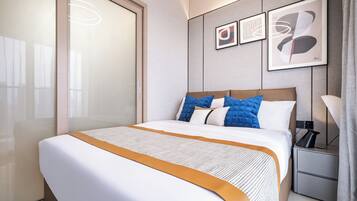 Une chambre d’hôtel avec un grand lit, une table de chevet, une lampe et des œuvres d’art accrochées au mur.