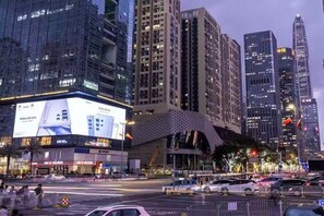 A cityscape with modern high-rise buildings, a large digital billboard, and a busy intersection. - Ge Rui  ApartmentFutian Shenzhen. (Futian District, Shenzhen.)
