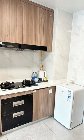 Uma cozinha compacta com armários de madeira, fogão a gás, lava-louças, geladeira e dispenser de água.