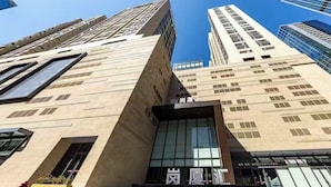 Un edificio moderno con una entrada destacada, amplios ventanales y un cielo despejado.