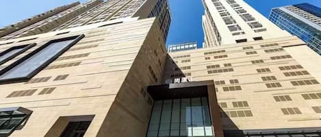 A modern building with a prominent entrance, large windows, and a clear sky.