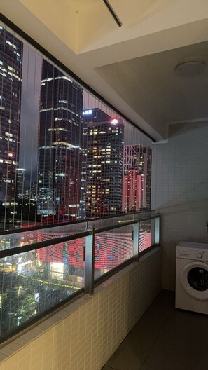 A view from a window with a metal railing, a tiled wall, and a washing machine in a corner. - Ge Rui  ApartmentFutian Shenzhen. (Futian District, Shenzhen.)