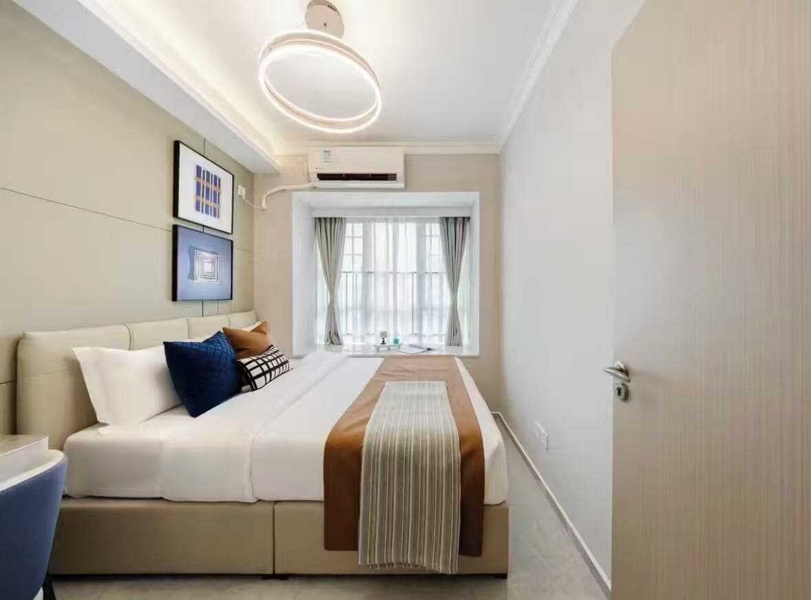 A modern hotel room with a bed, a desk, and a window with curtains.