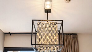 Een moderne kamer met een groot raam, een bijzondere geometrische lamp en uitzicht op een stadsbeeld.