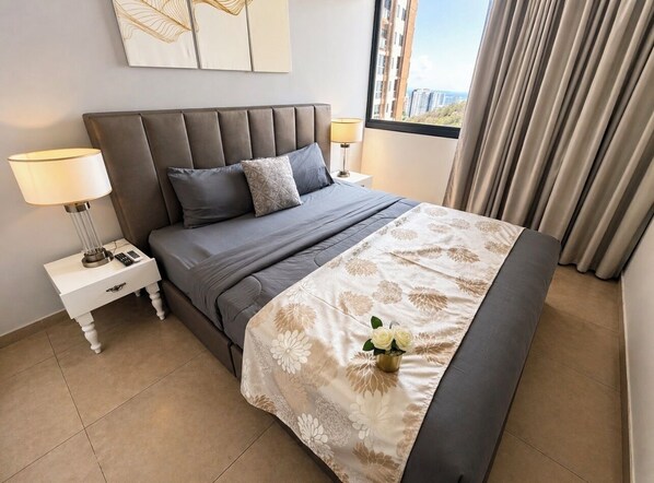 Ein modernes Hotelzimmer mit einem großen Bett, einem Nachttisch mit Lampe, einer Vase mit Blumen und Blick auf die Stadt durch das Fenster.