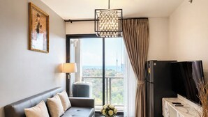 Een moderne woonkamer met een bank, salontafel, televisie en een groot raam met uitzicht over de stad.
