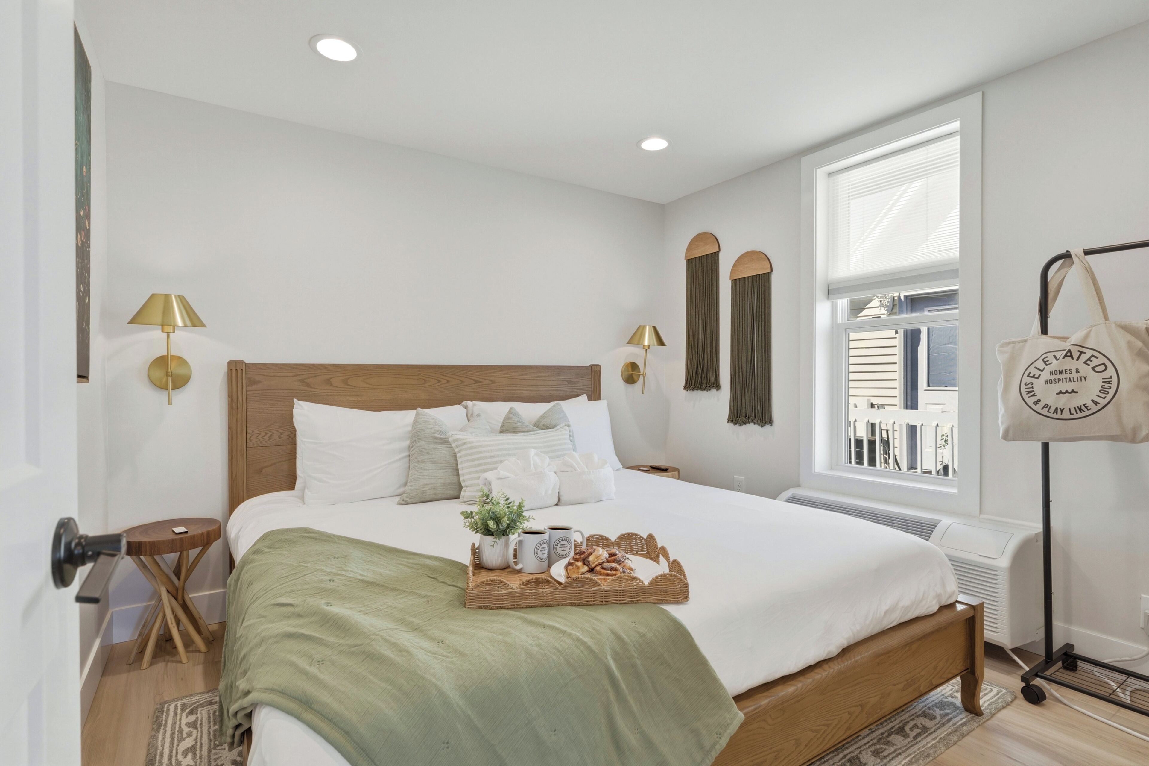 A neatly arranged bedroom with a bed, bedside lamps, a window, and a bedside table.