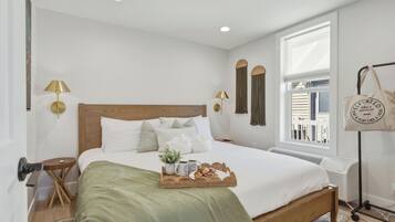 A neatly arranged bedroom with a bed, bedside lamps, a window, and a bedside table.