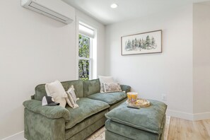 Een groene bank met kussens, een bak popcorn en een lijst met foto aan de muur.