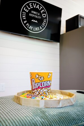 Een popcornbakje op een dienblad, met een bord in de achtergrond.
