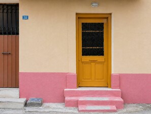 Une porte jaune avec un panneau de verre noir, une porte marron sur la gauche et un mur rose.