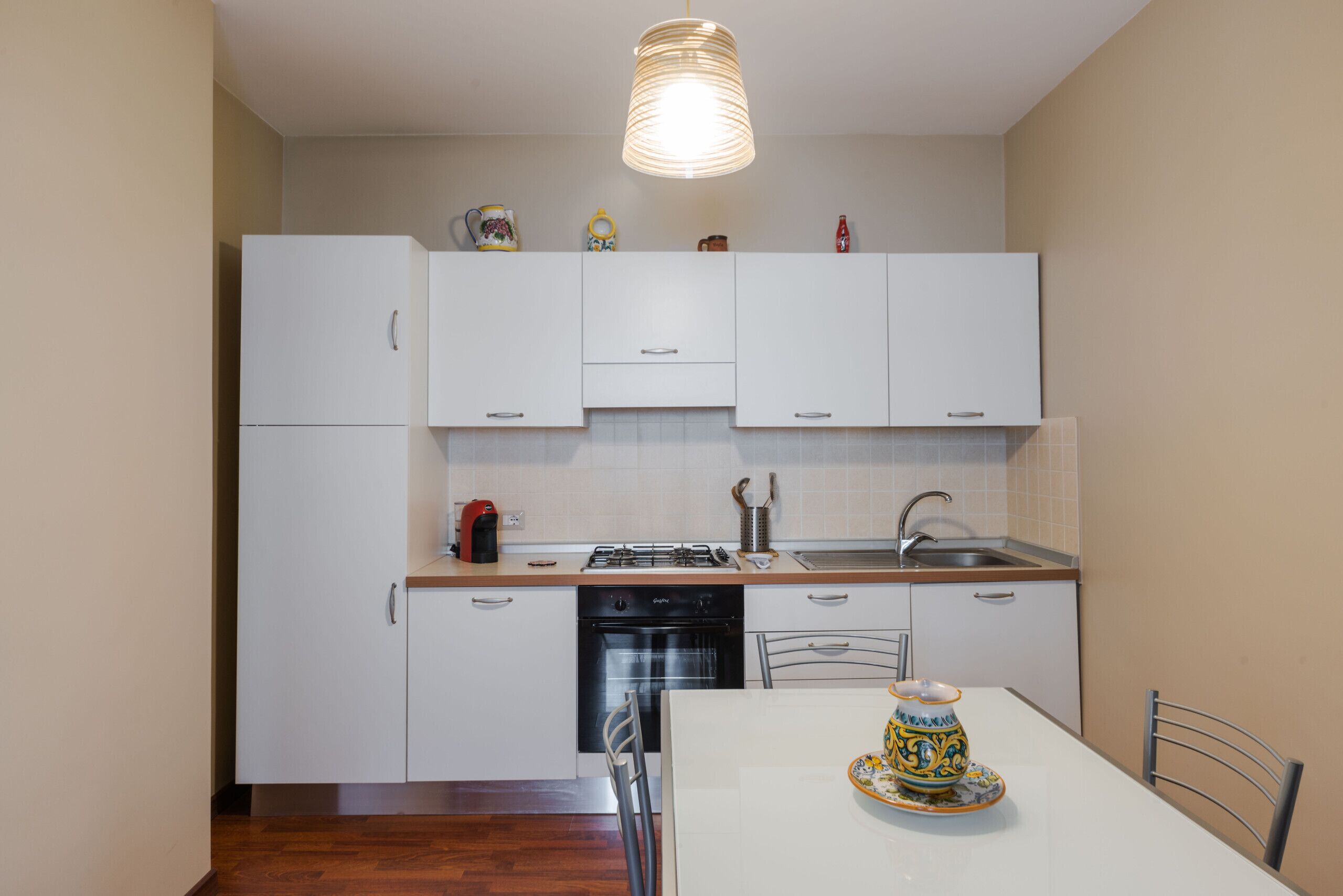 Une cuisine de taille réduite avec des meubles blancs, un lave-vaisselle, une cuisinière et un évier.