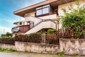 Ein zweigeschossiges Gebäude mit Balkon, Treppe und einer Betonwand.
