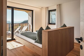 Un dormitorio con cama de madera, vista al exterior y balcón con sillas.