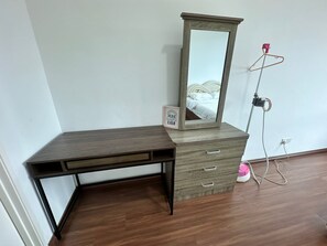 A wooden desk with drawers and a mirror, a hanging light, and a power outlet on the floor. - Trival Celes Homestay @ Sri Indah Sandakan (Sandakan)