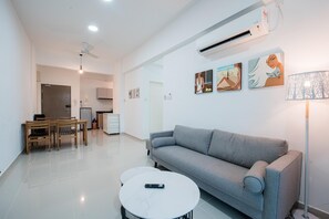 A modern living room with a grey sofa, a round coffee table, and a dining area with a wooden table and chairs. - Trival Celes Homestay @ Sri Indah Sandakan (Sandakan)