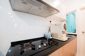 A modern kitchen with a black countertop, stainless steel range hood, and a coffee machine. - Trival Celes Homestay @ Sri Indah Sandakan (Sandakan)