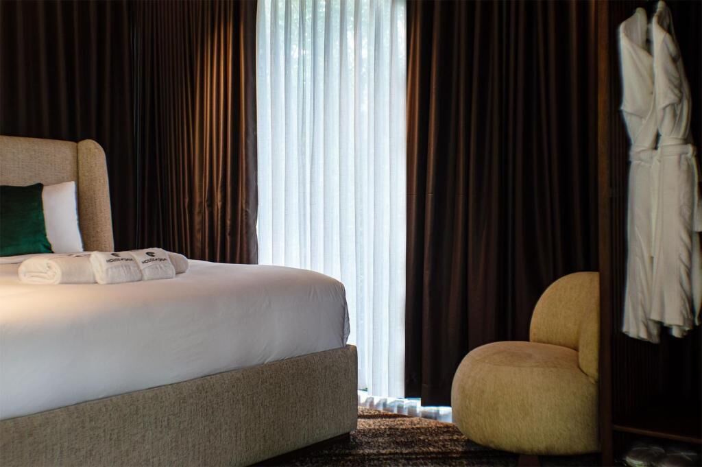 A hotel room with a bed, a chair, and a robe hanging on a door.