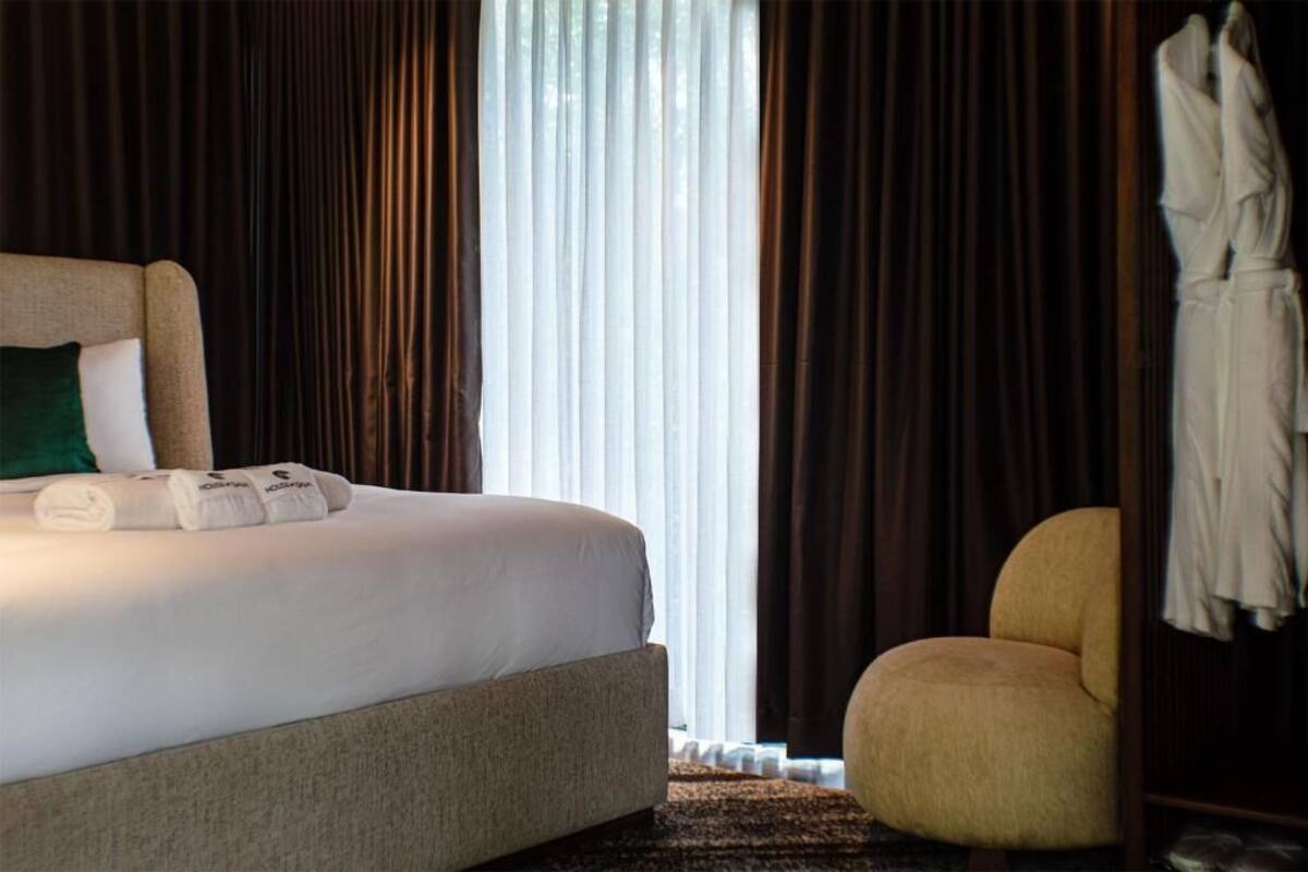 Habitación de hotel con una cama, una silla y una bata colgada en la puerta.