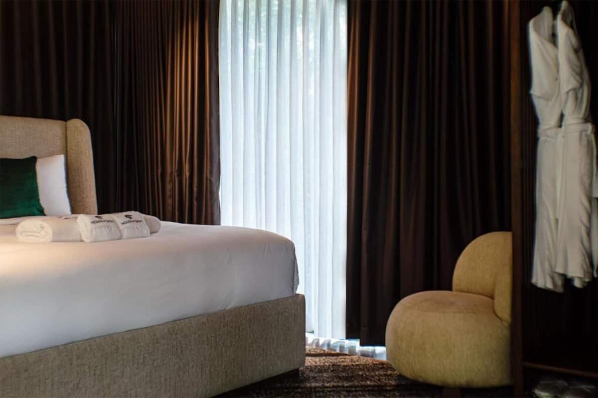 Une chambre dâhĂŽtel avec un lit, une chaise et un peignoir accrochĂ© Ă la porte.