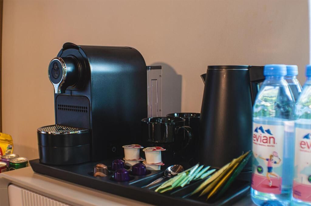A coffee machine, kettles, and water bottles on a counter.