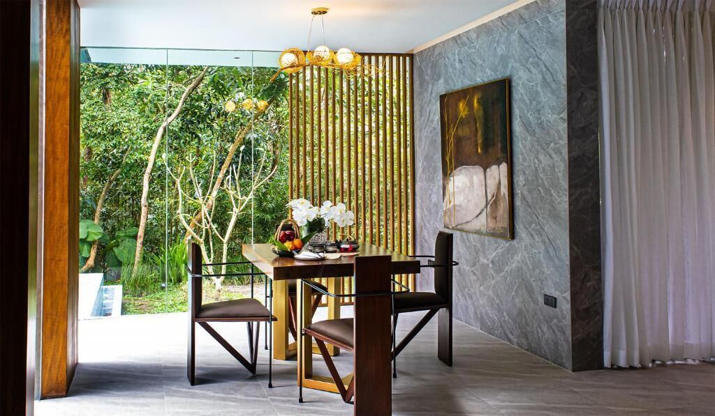 A dining area with a table, chairs, a vase of flowers, and a bamboo screen.