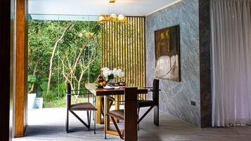 A dining area with a table, chairs, a vase of flowers, and a bamboo screen.