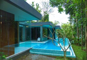 Uma casa moderna com piscina envidraçada, cercada por vegetação exuberante.