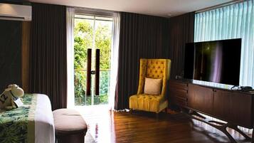 A hotel room with a bed, a chair, a desk, a TV, and a sliding glass door to a balcony.