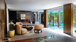 A modern living room with a fireplace, comfortable seating, and a glass door leading to a pool. - House of Gaia (Lipa City)
