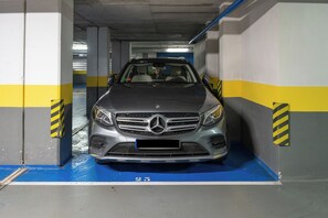 A parking garage with a Mercedes-Benz car parked in a bay marked with the number 25.