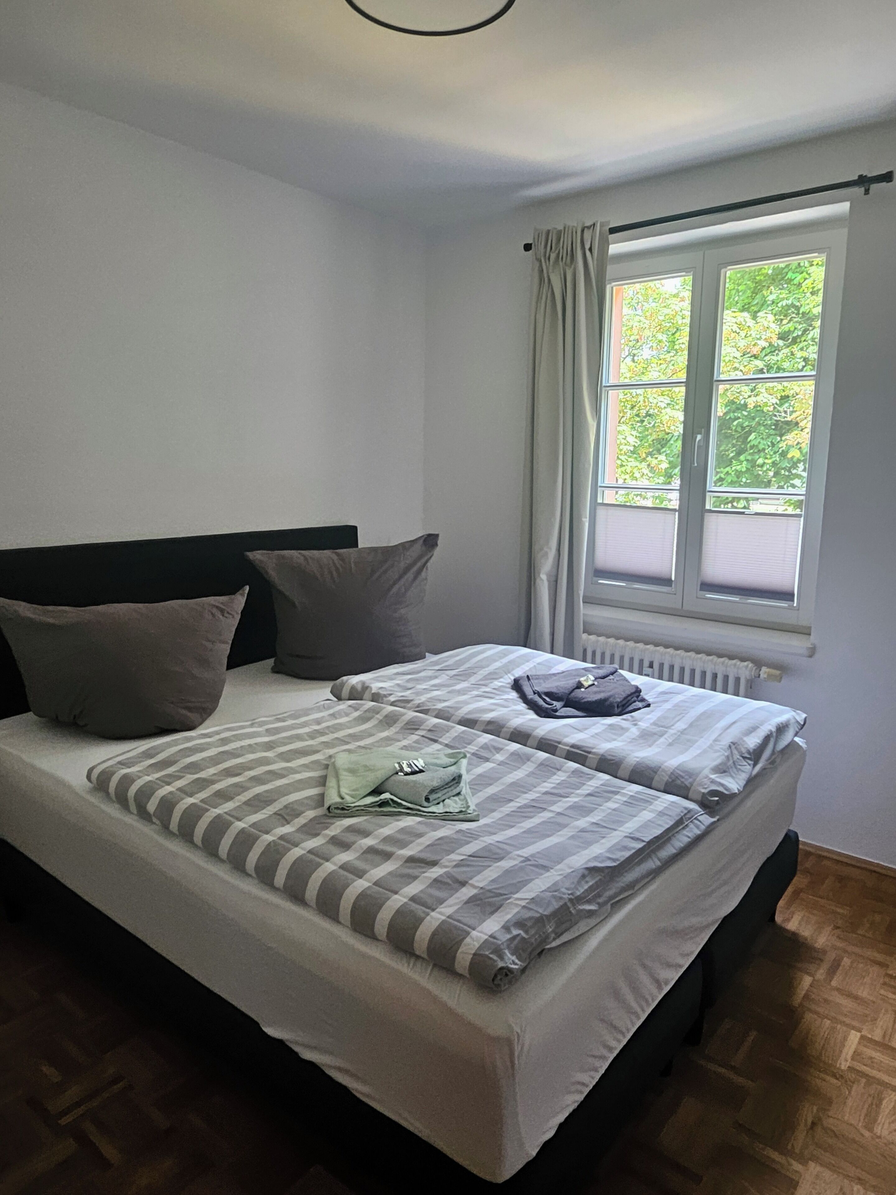 Ein Schlafzimmer mit zwei Betten, einem Fenster mit Vorhängen und einer Heizung.