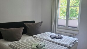 Un dormitorio con dos camas, una ventana con cortinas y un radiador.