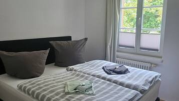 Ein Schlafzimmer mit zwei Betten, einem Fenster mit Vorhängen und einer Heizung.
