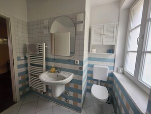 A bathroom with a sink, mirror, toilet, and a window. - Centrally located vacation apartment with a balcony overlooking the lake. 250 m from Rheinsberg Castle (Rheinsberg)