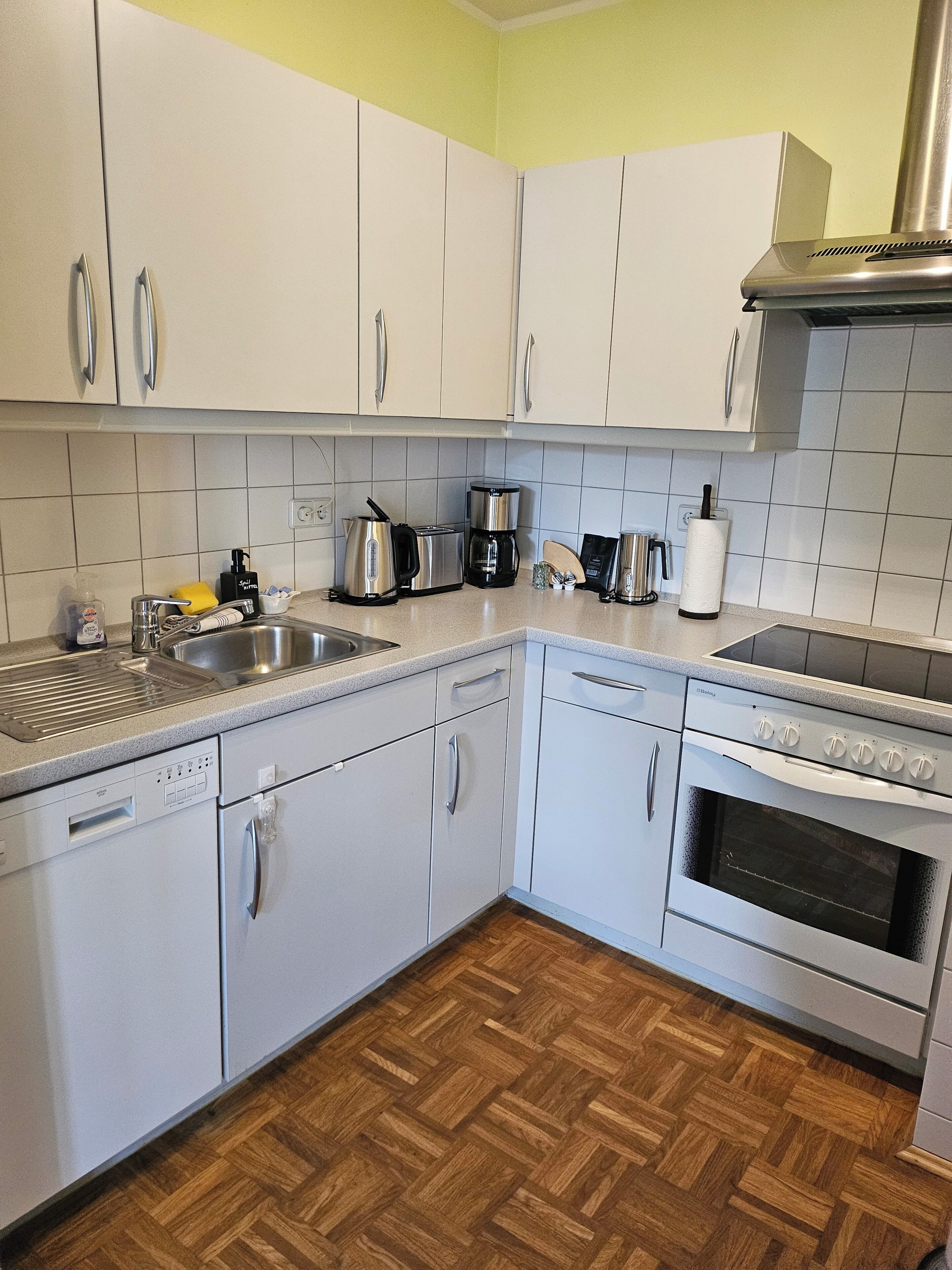 A kitchen with white cabinets, a dishwasher, a stove, and a coffee maker.