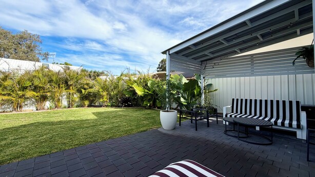 A patio with a black and white striped bench, a white planter, and a white fence.
