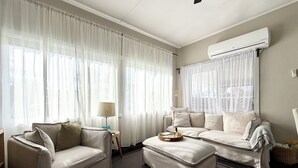 A living room with a sofa, ottoman, and a lamp.
