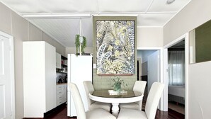 A dining area with a round table, four chairs, and a hanging plant.