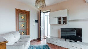 Un salon avec un canapé, un téléviseur et un tapis à motifs.